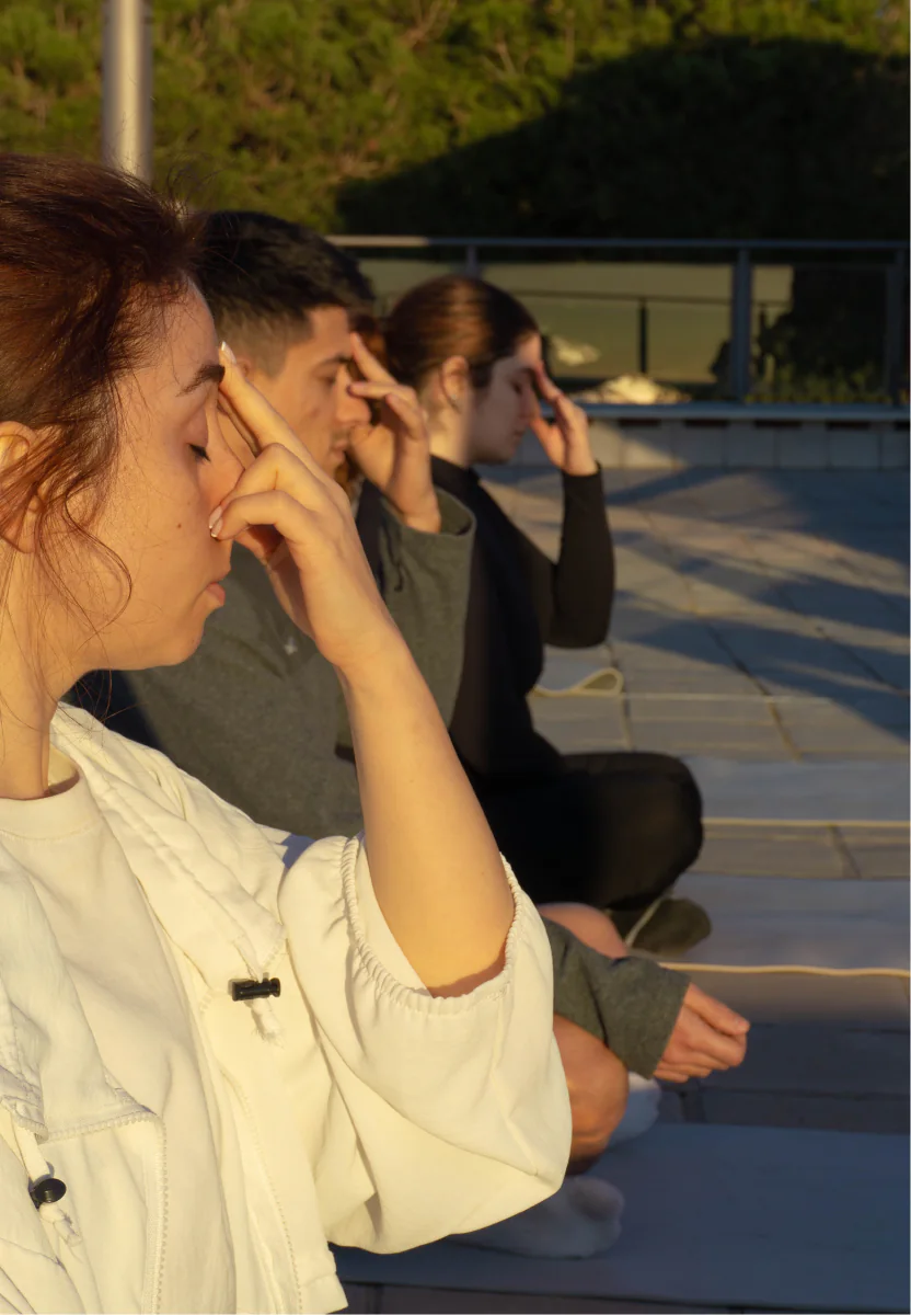 Three people practice breathing exercises together during the rooftop yoga session.